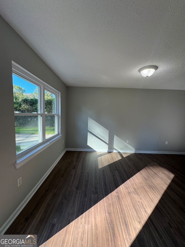 empty room with a textured ceiling and dark hardwood / wood-style floors