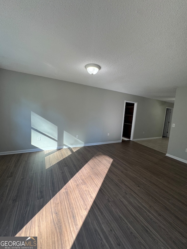 unfurnished room with dark hardwood / wood-style flooring and a textured ceiling