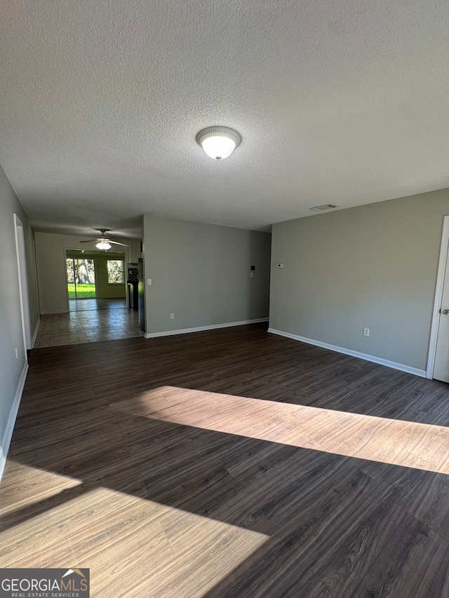 spare room with a textured ceiling and dark wood-type flooring