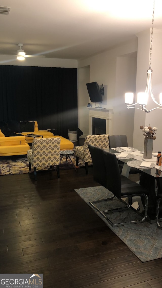 dining area with ceiling fan with notable chandelier and dark wood-type flooring