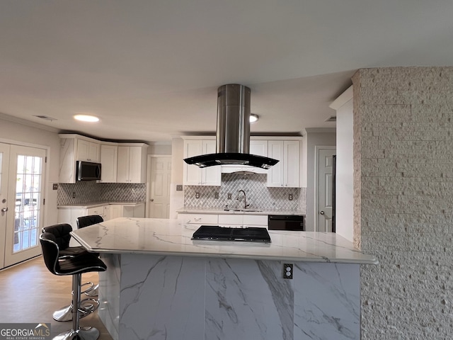 kitchen with island exhaust hood, a kitchen breakfast bar, white cabinets, and sink