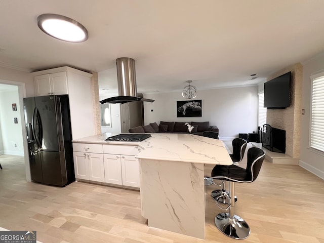 kitchen featuring white cabinetry, black refrigerator with ice dispenser, island range hood, and stainless steel gas stovetop