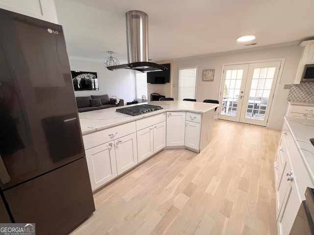 kitchen featuring white cabinetry, french doors, stainless steel appliances, island exhaust hood, and decorative backsplash