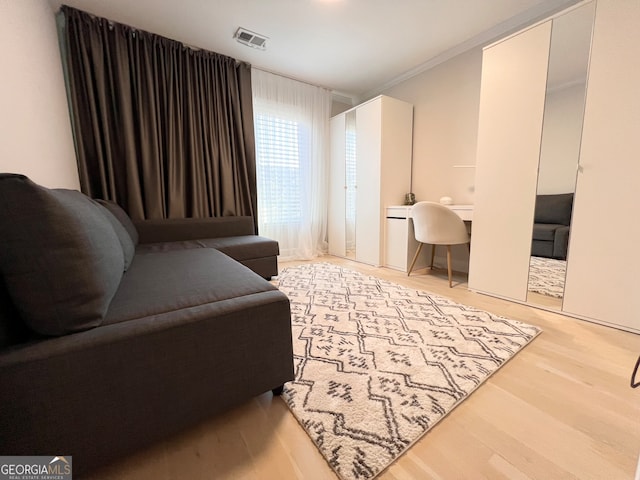 living area featuring ornamental molding and light wood-type flooring