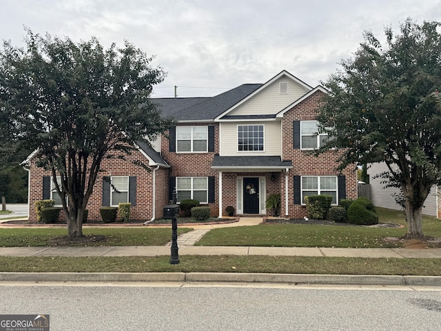 view of front facade featuring brick siding, a front yard, and a shingled roof