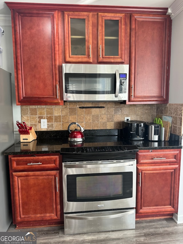 kitchen with hardwood / wood-style floors, backsplash, stainless steel appliances, and crown molding