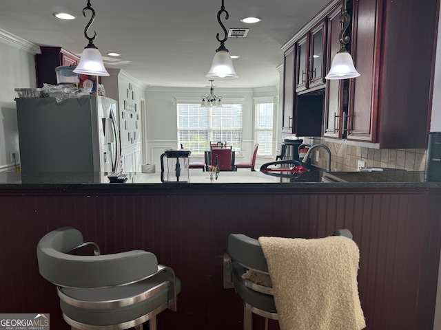 kitchen featuring hanging light fixtures, tasteful backsplash, kitchen peninsula, stainless steel fridge, and ornamental molding