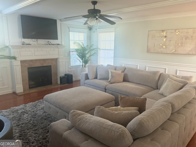 living room featuring ceiling fan, wood-type flooring, ornamental molding, and a tiled fireplace