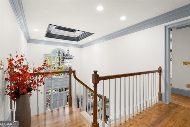 stairs featuring ornamental molding, a chandelier, hardwood / wood-style floors, and a raised ceiling