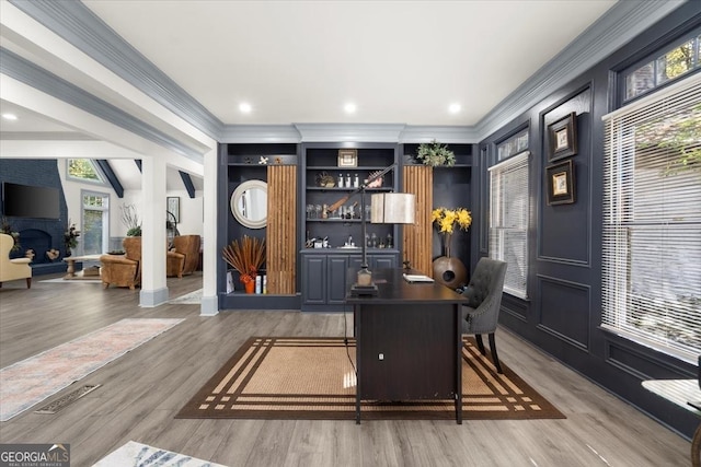 office featuring wood-type flooring, a healthy amount of sunlight, and a fireplace