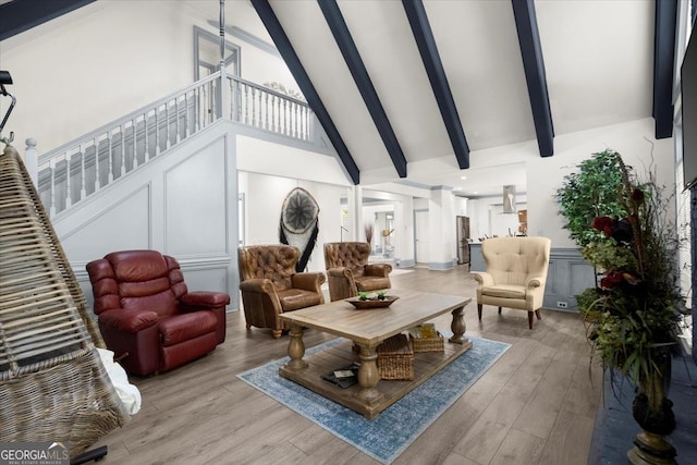 living room featuring beamed ceiling, high vaulted ceiling, and light hardwood / wood-style floors