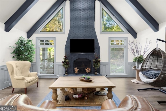 living room featuring hardwood / wood-style flooring, a fireplace, high vaulted ceiling, and beam ceiling