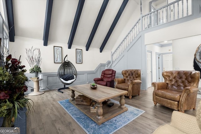 living room featuring beamed ceiling, light wood-type flooring, and high vaulted ceiling