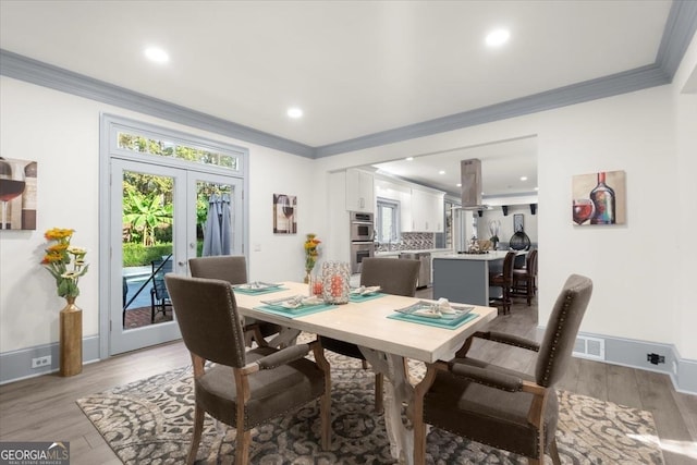 dining area featuring french doors, ornamental molding, and light hardwood / wood-style flooring