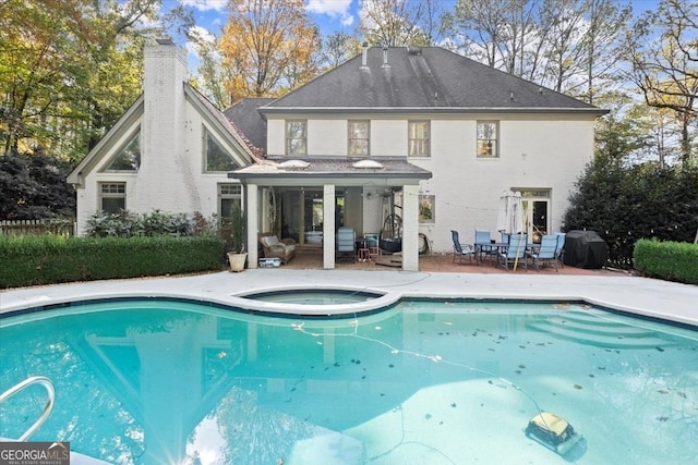 rear view of property featuring a swimming pool with hot tub, a patio, and an outdoor living space