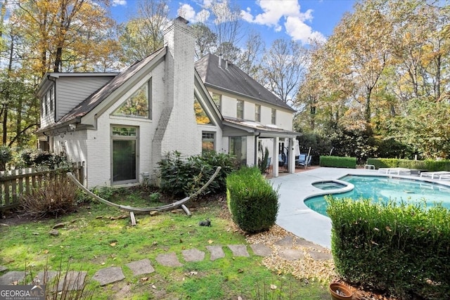 rear view of house with a swimming pool with hot tub and a patio area