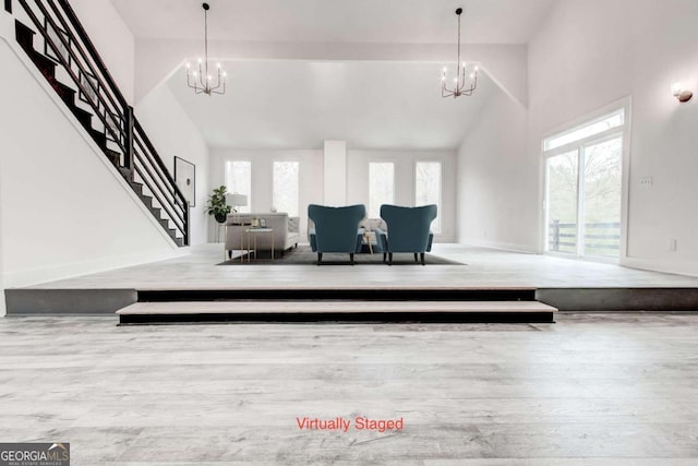 interior space with high vaulted ceiling, an inviting chandelier, a wealth of natural light, and light hardwood / wood-style flooring