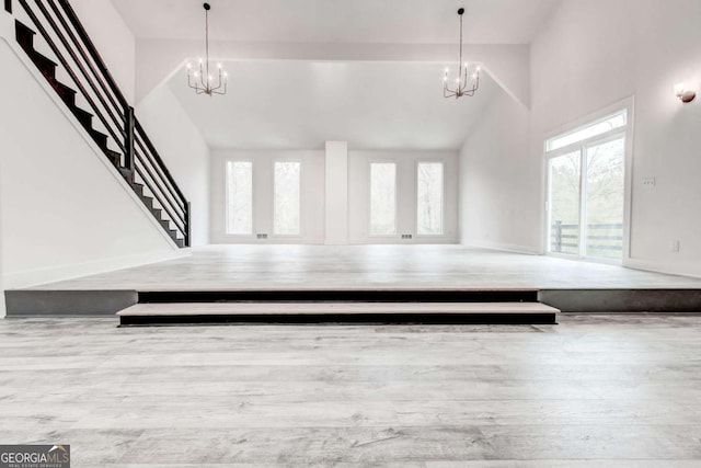 entrance foyer featuring light wood-type flooring, high vaulted ceiling, and a chandelier