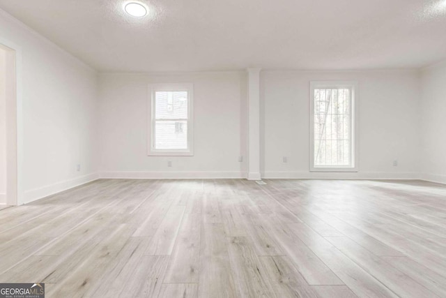 empty room with light wood-type flooring and a textured ceiling