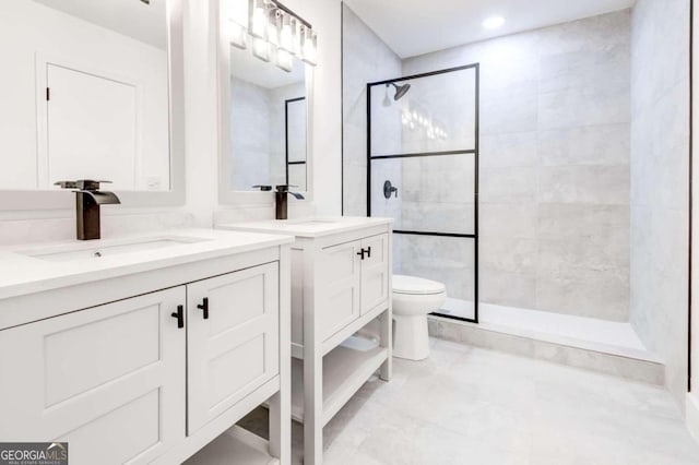 bathroom with a tile shower, vanity, and toilet