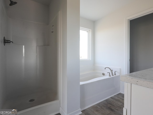 bathroom with a bath, walk in shower, and wood finished floors