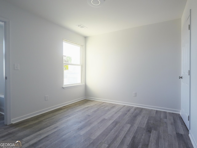 unfurnished bedroom featuring dark wood-style flooring, visible vents, and baseboards