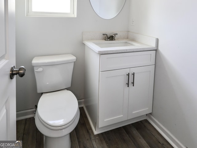 half bathroom featuring toilet, wood finished floors, vanity, and baseboards