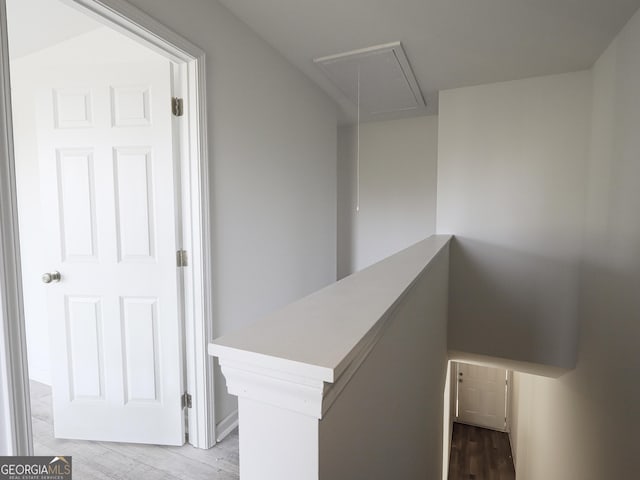 staircase featuring wood finished floors and attic access