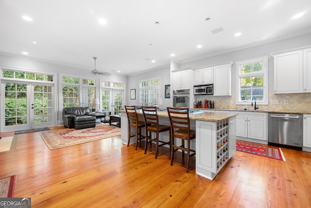 kitchen featuring white cabinets, a wealth of natural light, a center island, and appliances with stainless steel finishes