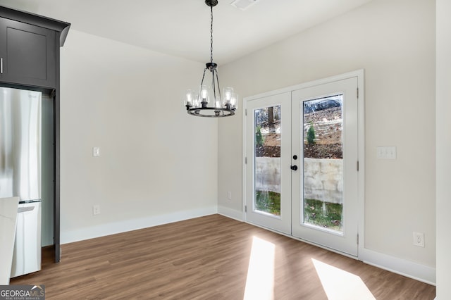 unfurnished dining area featuring dark hardwood / wood-style floors, a chandelier, and french doors