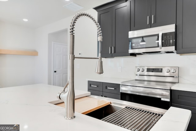 kitchen featuring tasteful backsplash, light stone countertops, sink, and stainless steel appliances