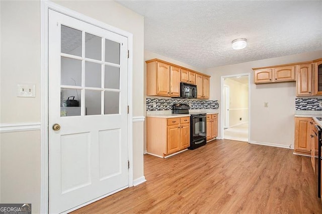 kitchen with backsplash, a textured ceiling, black appliances, light brown cabinets, and light hardwood / wood-style flooring