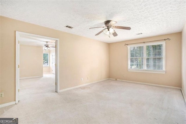 carpeted empty room with ceiling fan and a textured ceiling