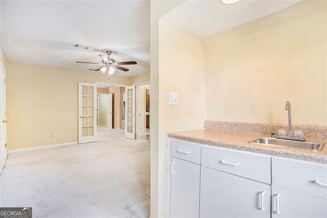 kitchen featuring ceiling fan, light colored carpet, sink, and french doors