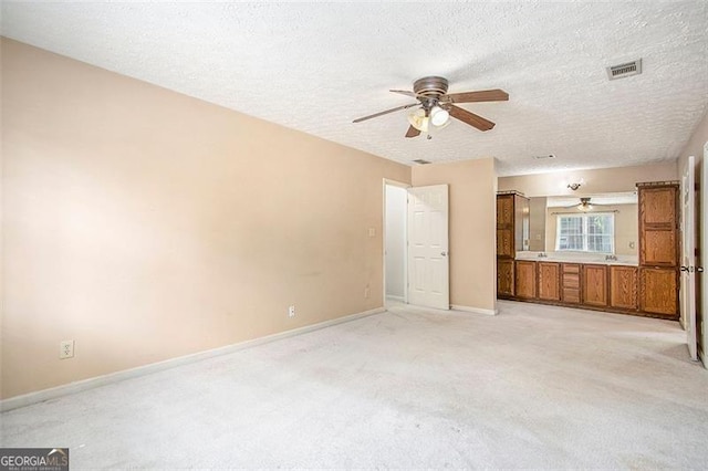 unfurnished bedroom featuring light carpet, a textured ceiling, and ceiling fan