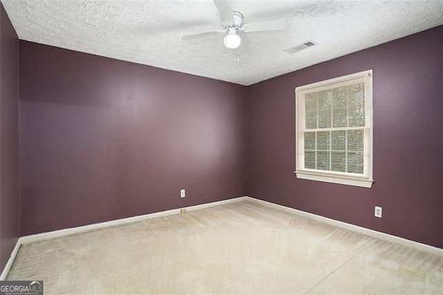 spare room featuring carpet flooring, ceiling fan, and a textured ceiling