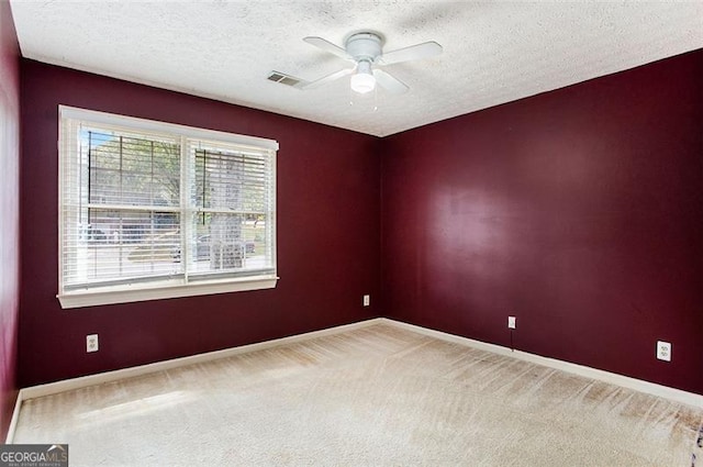 carpeted spare room with ceiling fan and a textured ceiling