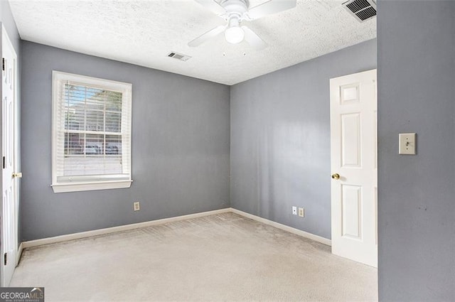 carpeted spare room featuring a textured ceiling and ceiling fan