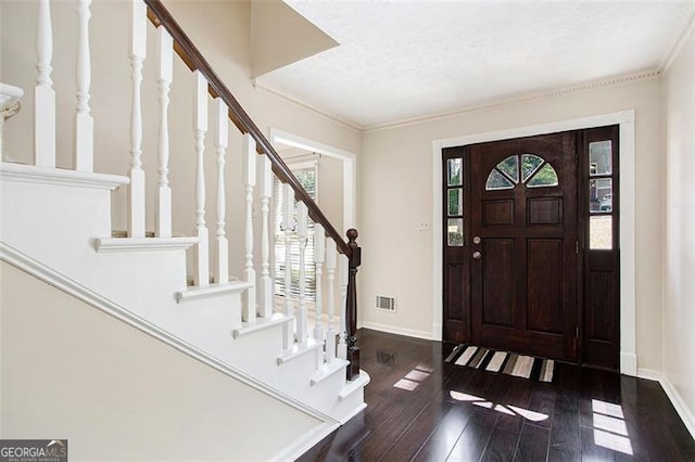 entryway featuring ornamental molding, a textured ceiling, a wealth of natural light, and dark wood-type flooring