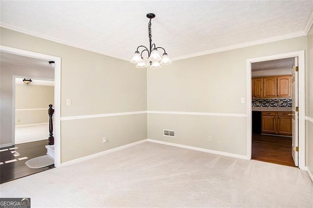 carpeted spare room featuring crown molding, a textured ceiling, and an inviting chandelier