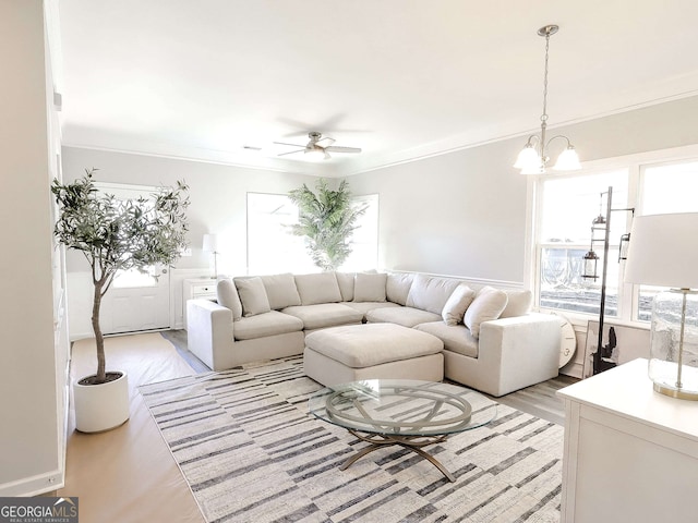 living room with crown molding, ceiling fan with notable chandelier, and light wood-type flooring