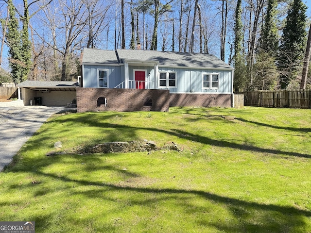 view of front of house with a chimney, fence, a front lawn, board and batten siding, and brick siding