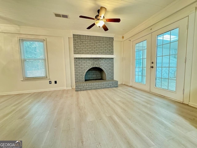 unfurnished living room with visible vents, a brick fireplace, ornamental molding, french doors, and wood finished floors