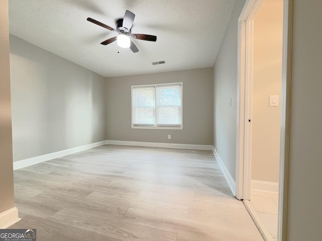 unfurnished room with light wood finished floors, visible vents, baseboards, a textured ceiling, and a ceiling fan