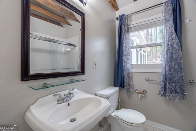 bathroom featuring toilet, baseboards, and a sink