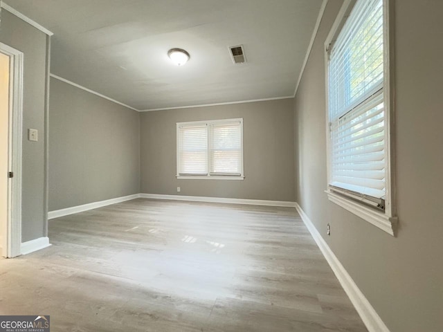 unfurnished room featuring crown molding, wood finished floors, visible vents, and baseboards