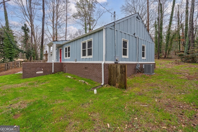 view of side of home featuring cooling unit, a yard, board and batten siding, and fence