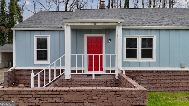 property entrance with a chimney, brick siding, and a shingled roof