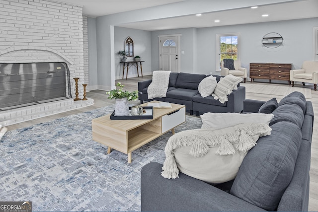 living room featuring light wood-type flooring and a brick fireplace