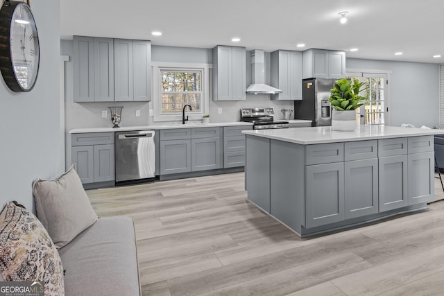 kitchen with gray cabinets, a wealth of natural light, wall chimney exhaust hood, and stainless steel appliances